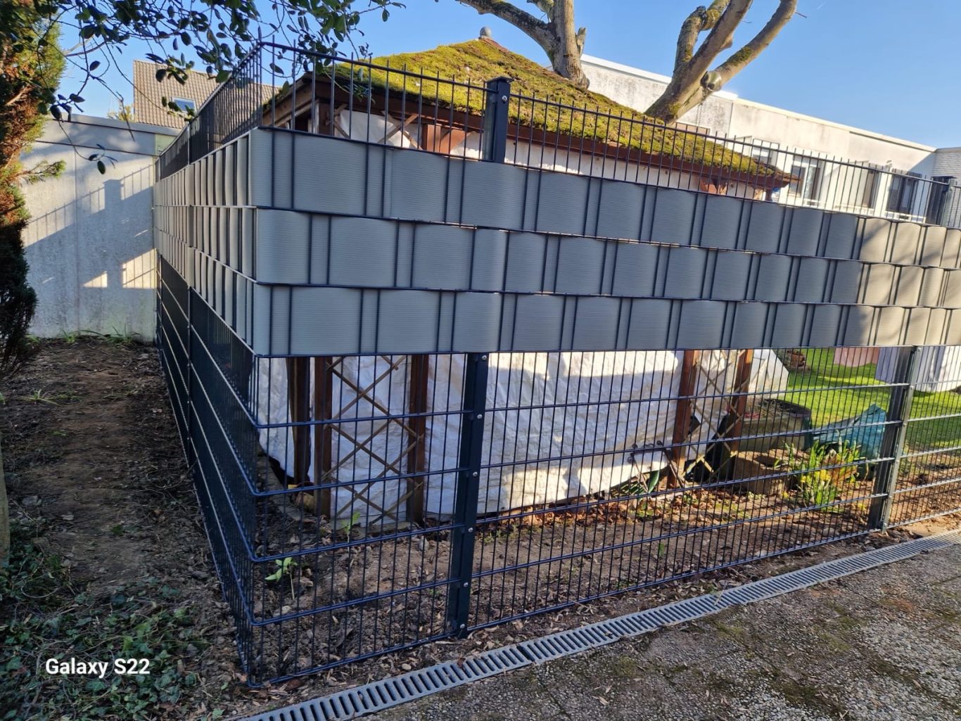 Zaunbau Langenfeld – Sichtschutzzaun im Eckbereich Ecklösung beim Zaunbau in Langenfeld: Doppelstabmattenzaun mit grauem Sichtschutz im oberen Bereich.